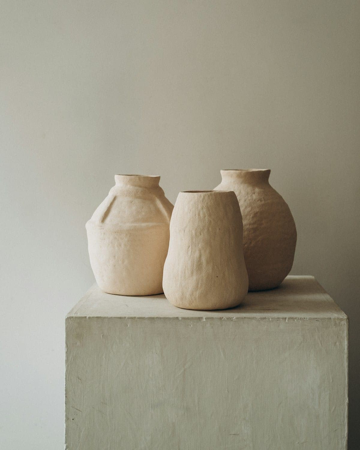 Three handmade clay vases on a stone plinth