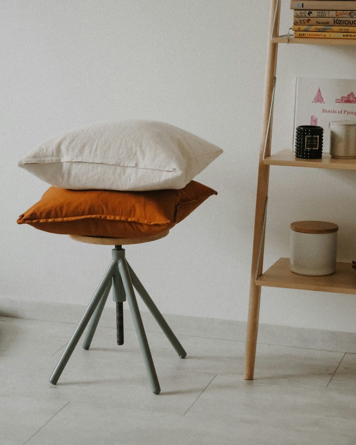 Ivory linen and rust velvet cushions stacked on a stool