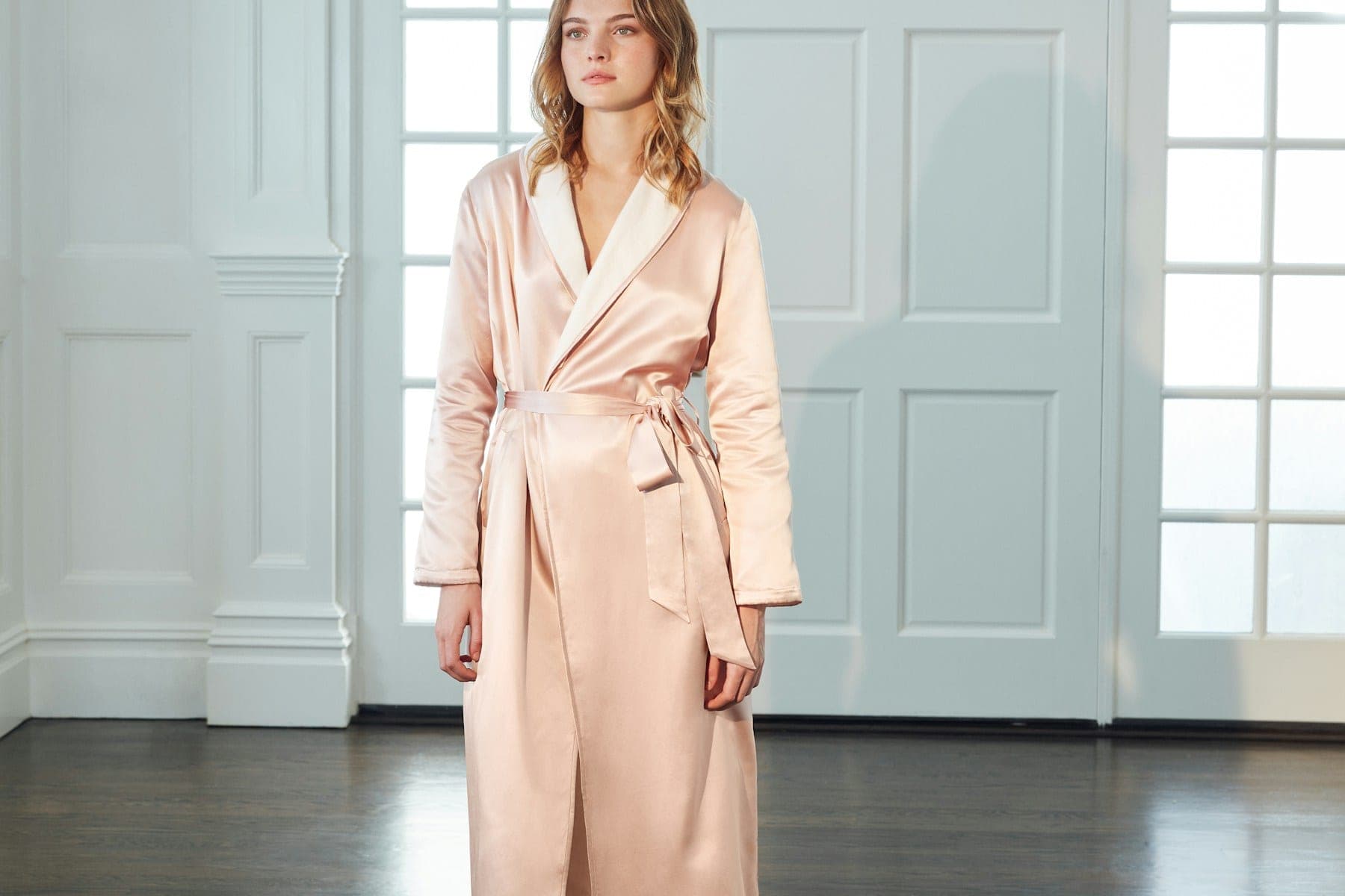Woman in a blush satin robe with ivory lapels